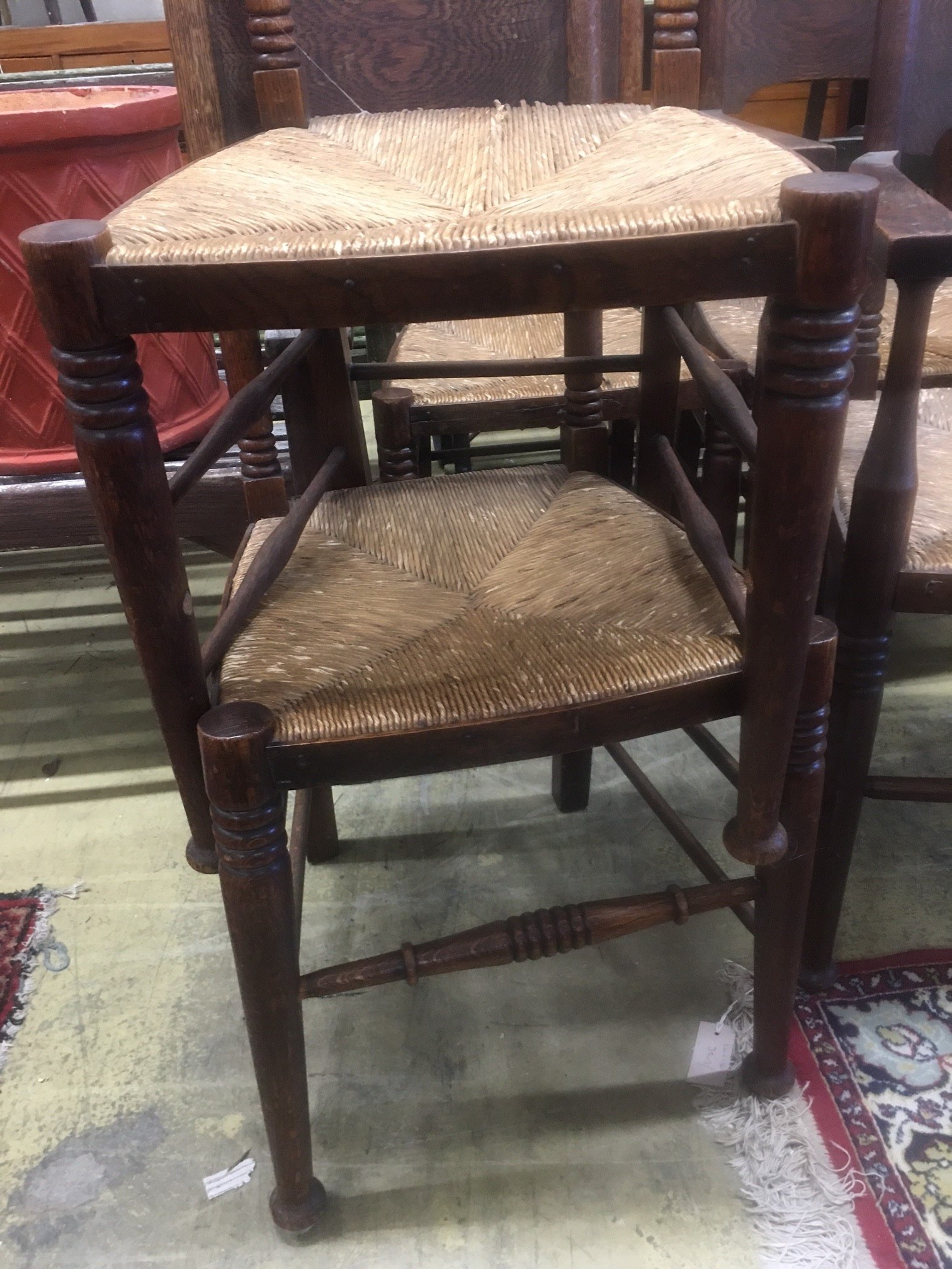 A set of six Arts & Crafts oak chairs, including a pair of carvers, in the Glasgow School manner by William Birch, High Wycombe, with shaped panels backs, ring turned frames and rush seats, carvers W.58cm D.54cm H.109cm